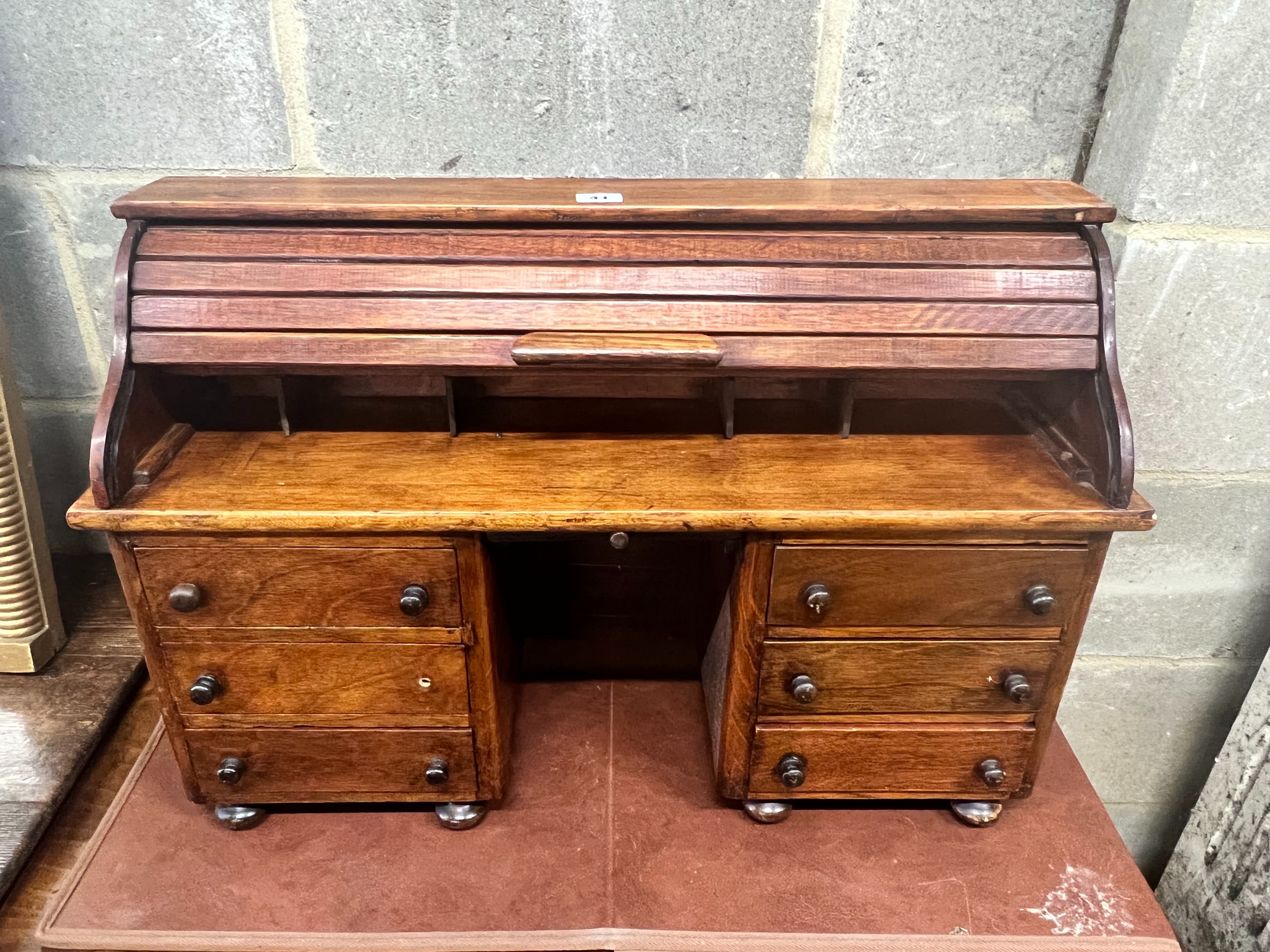 A miniature mahogany and hardwood kneehole tambour desk, width 69cm, depth 22cm, height 45cm.